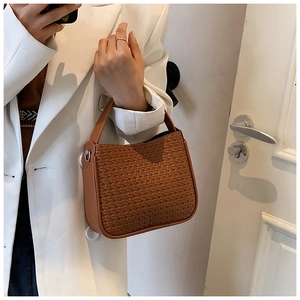 Detailed view of a brown woven pattern handbag held by a model for a chic fall style