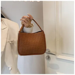Brown woven texture handbag detail shown with elegant white blazer for autumn fashion