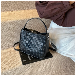 Detail of black woven handbag with silver metal hardware and adjustable shoulder strap
