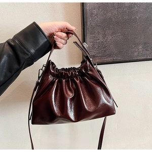 Detail view of burgundy pleated dumpling bag showing glossy finish and soft leather texture