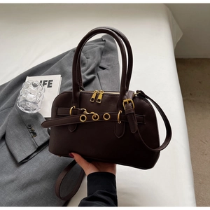 Close-up of dark brown Boston handbag with gold metal hardware and leather texture details