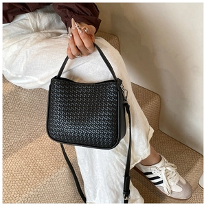 Detail of a vintage black woven leather handbag with metallic hooks and long shoulder strap