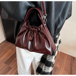 Close-up of wine red pleated cloud bag featuring glossy finish and silver hardware