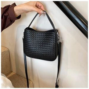Close-up of black woven leather handbag showing detailed texture and silver hardware