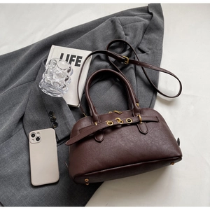 Close-up of retro brown leather handbag on a grey suit with elegant gold metal feet