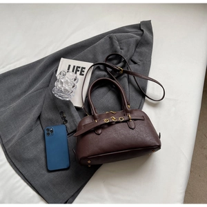 Flat lay of a vintage brown leather handbag with buckle details and adjustable strap
