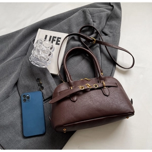 Detail of dark brown lychee texture handbag with bronze hardware and adjustable strap