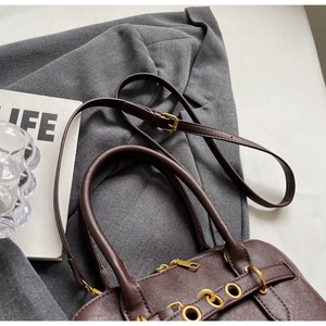 Top view of dark brown lychee grain leather handbag with gold hardware on grey suit