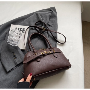 Detail of dark brown leather handbag with gold metal eyelets and textured finish