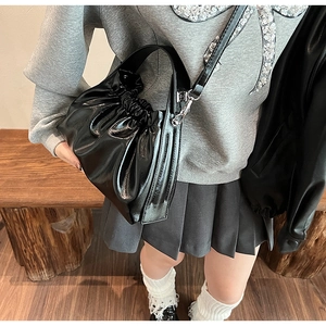 Close-up of black pleated cloud bag with soft faux leather texture and silver buckle