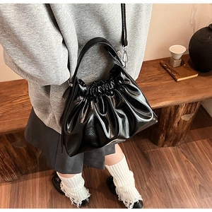 Detail of black glossy pleated cloud bag with elegant gathers and detachable strap