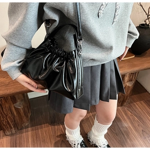 Detail of black glossy pleated cloud bag with leather texture and versatile straps