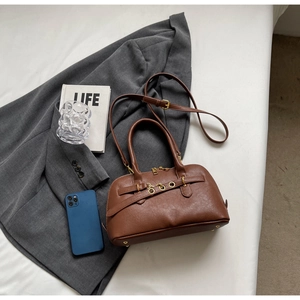 Detail view of brown faux leather handbag with gold metal eyelets and chain accents