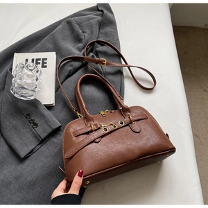 Detail showing high-quality leather texture and vintage gold buckle on a brown handbag