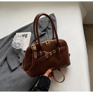 Detailed macro view of vintage brown leather handbag with gold metal zippers and buckles