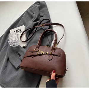 Macro shot of dark brown matte leather bag with belt buckle detail and metal rings