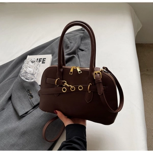 Close-up of a dark brown handbag with gold zippers and adjustable strap for commuting