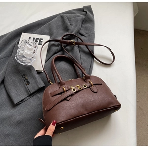 Detail of vintage dark brown handbag with gold eyelets and bottom metal feet protection