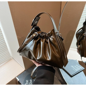 Detailed view of dark brown glossy ruched handbag with metallic buckle and leather texture