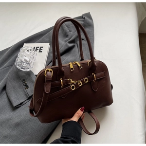 Detail of a dark brown Boston bag with double zippers, gold rings and adjustable strap