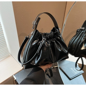 Detail of black glossy cloud bag with pleated texture and silver chain hardware