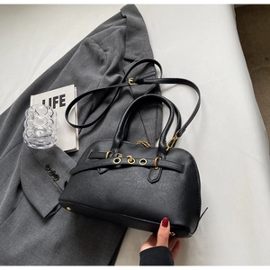 Detail of black leather Boston bag featuring gold eyelet strap and dual handles