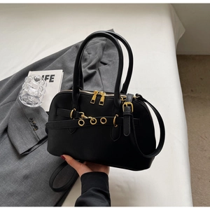 Detail of black leather handbag with gold metal buckles and adjustable crossbody strap