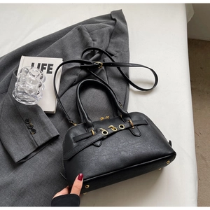 Detail of a black leather handbag with gold metal feet on white background with props
