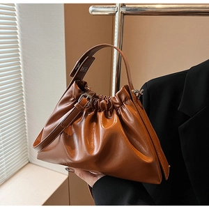 Detail of vintage brown ruched cloud handbag with polished faux leather and top handle