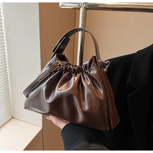 Detail of dark brown pleated cloud bag with glossy faux leather texture and silver buckle