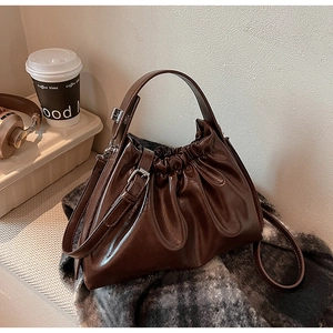 Detail of dark brown pleated cloud bag featuring glossy texture and silver metal buckle