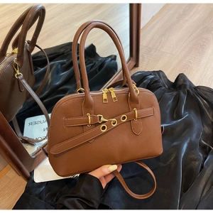 Detail of vintage brown PU leather handbag with gold zippers and adjustable strap