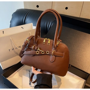 Detail view of caramel brown Boston bag with golden hardware and leather strap