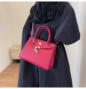 Dettaglio di una borsa in pelle rossa testurizzata con chiusura a scatto oro su modella
