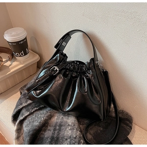 Detail of a black pleated cloud bag with glossy texture and silver metal hardware
