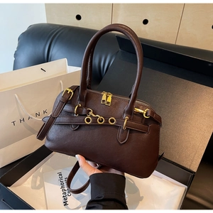 Detail of dark brown lychee leather handbag with golden hardware and belt buckle accents