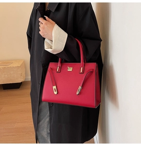 Borsa da sposa rossa con dettagli dorati abbinata a un elegante cappotto nero