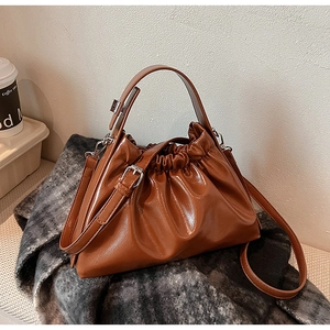 Detail of a brown ruched cloud handbag with glossy PU texture and silver hardware