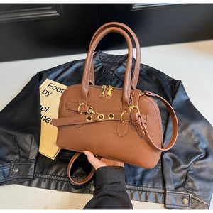 Detail of caramel brown doctor bag with golden hardware, rivets, and chain on leather jacket