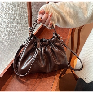Detail of dark brown ruched cloud bag showing glossy faux leather and fine stitching