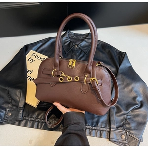 Close-up of brown leather bowling bag with gold eyelet accents and chain detail
