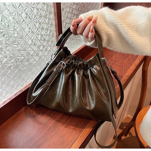 Detail view of olive green ruched handbag with glossy leather and metallic buckle