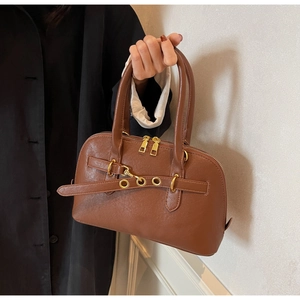 Detailed view of brown faux leather bowling bag with gold eyelets and dual zippers