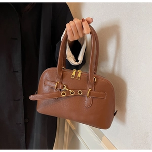 Detail of dark brown leather handbag featuring golden double zippers and metal eyelets