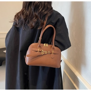 Detailed side view of the dark brown Boston bag with golden metal hardware on model