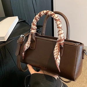 Vintage donkerbruine leren crossbodytas met zijden sjaal aan handvat op achtergrond