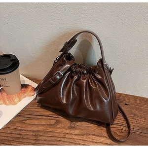 Detail of dark brown glossy cloud bag with pleated texture and stylish drawstring