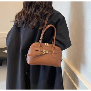 Detailed view of caramel brown leather handbag with gold eyelets and textured finish