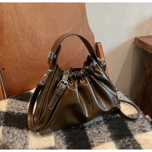 Detail of dark brown pleated cloud bag with shiny finish and silver metal buckles