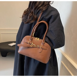 Detail view of the brown leather bag with golden ring buckle and dual zipper design